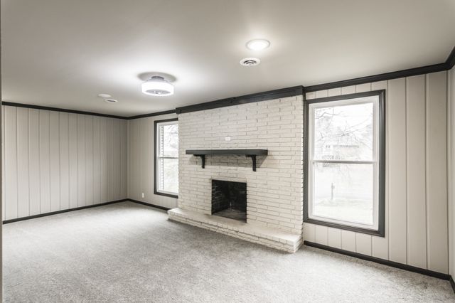a view of an empty room with a fireplace and a window