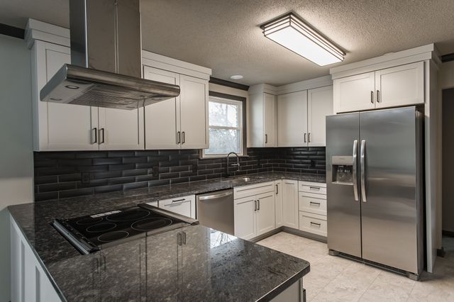 a kitchen with stainless steel appliances granite countertop a stove a refrigerator a sink dishwasher and white countertops with cabinets