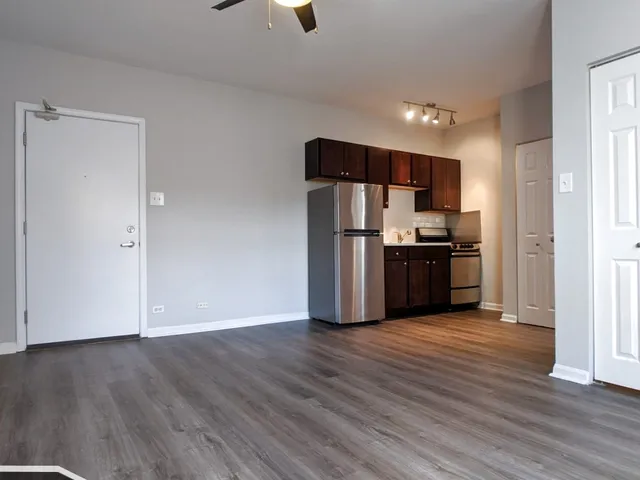 a view of kitchen with stainless steel appliances wooden floor and an empty room