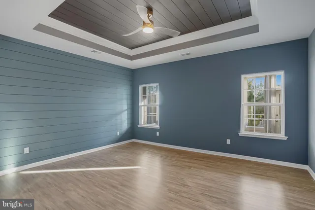 a view of an empty room with wooden floor fireplace and a window
