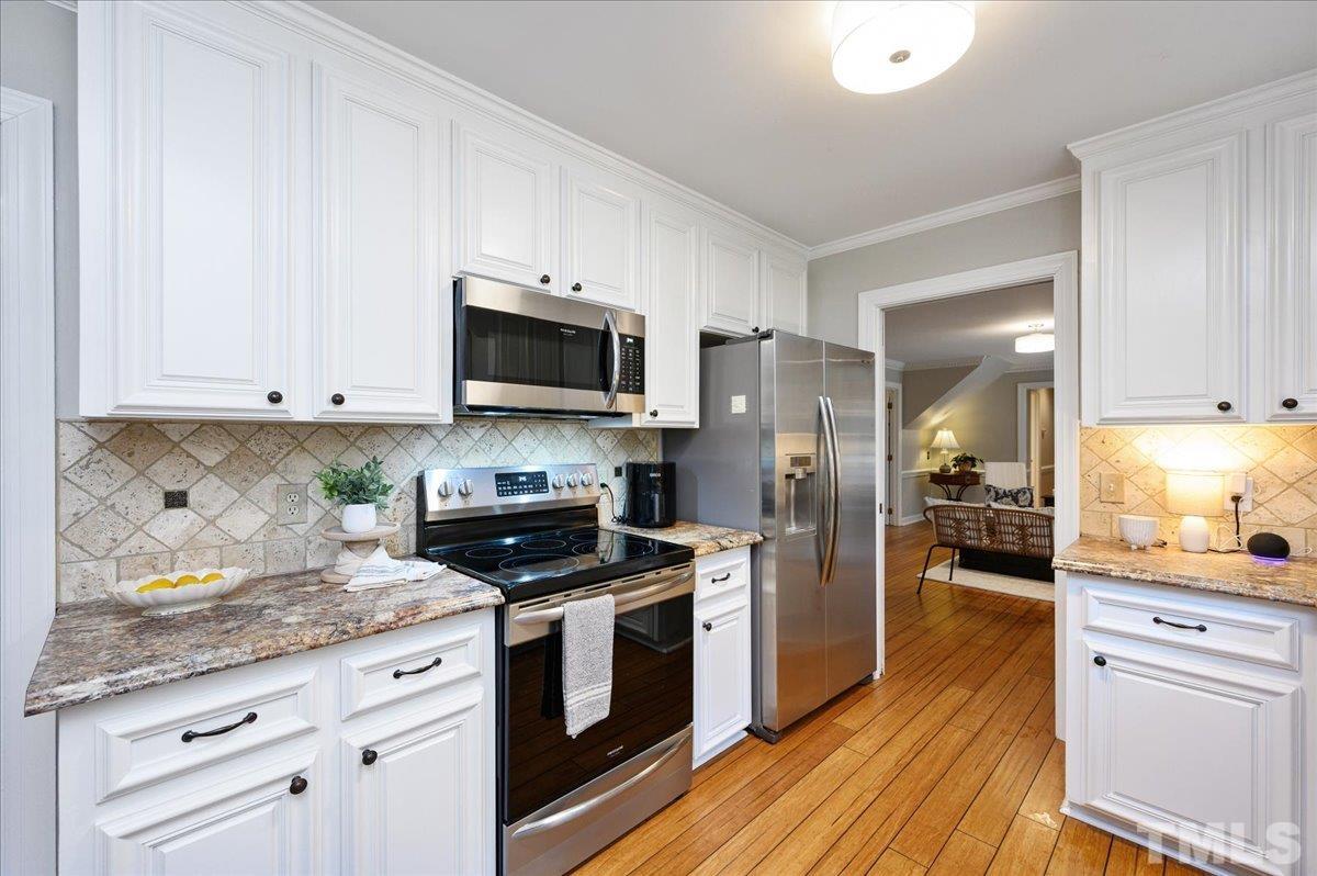 5101 Fielding Drive Raleigh, NC 27606 - Photo 14 of 32 a kitchen with stainless steel appliances granite countertop a refrigerator a stove top oven a sink dishwasher and white cabinets with wooden floor