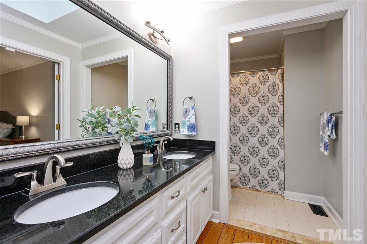 5101 Fielding Drive Raleigh, NC 27606 - Photo 23 of 32 a bathroom with double vanity sinks a toilet a mirror and shower