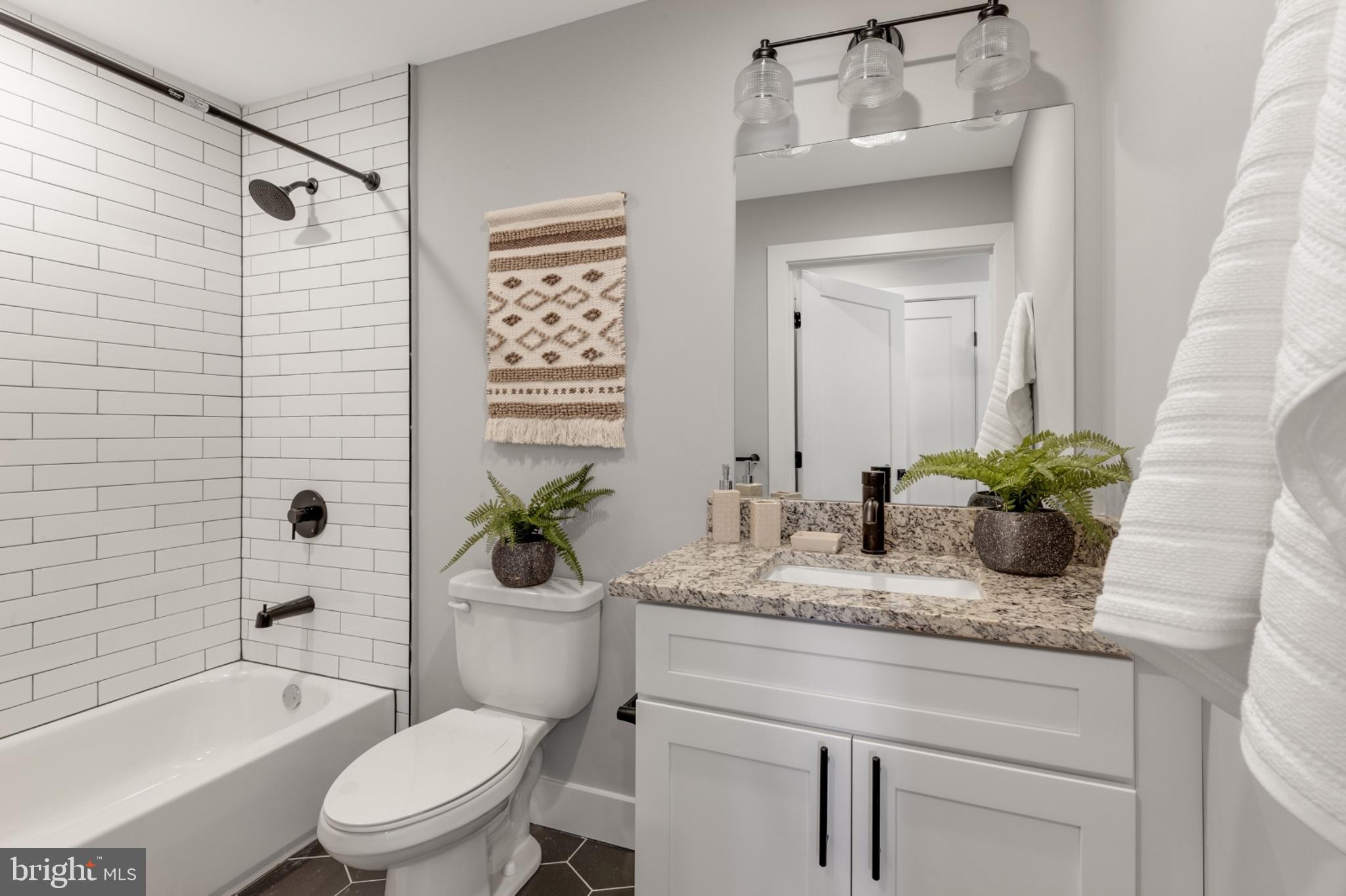 1924 North Front Street, Unit 401 Philadelphia, PA 19122 - Photo 15 of 30 a bathroom with a granite countertop sink a toilet a mirror a bathtub and shower