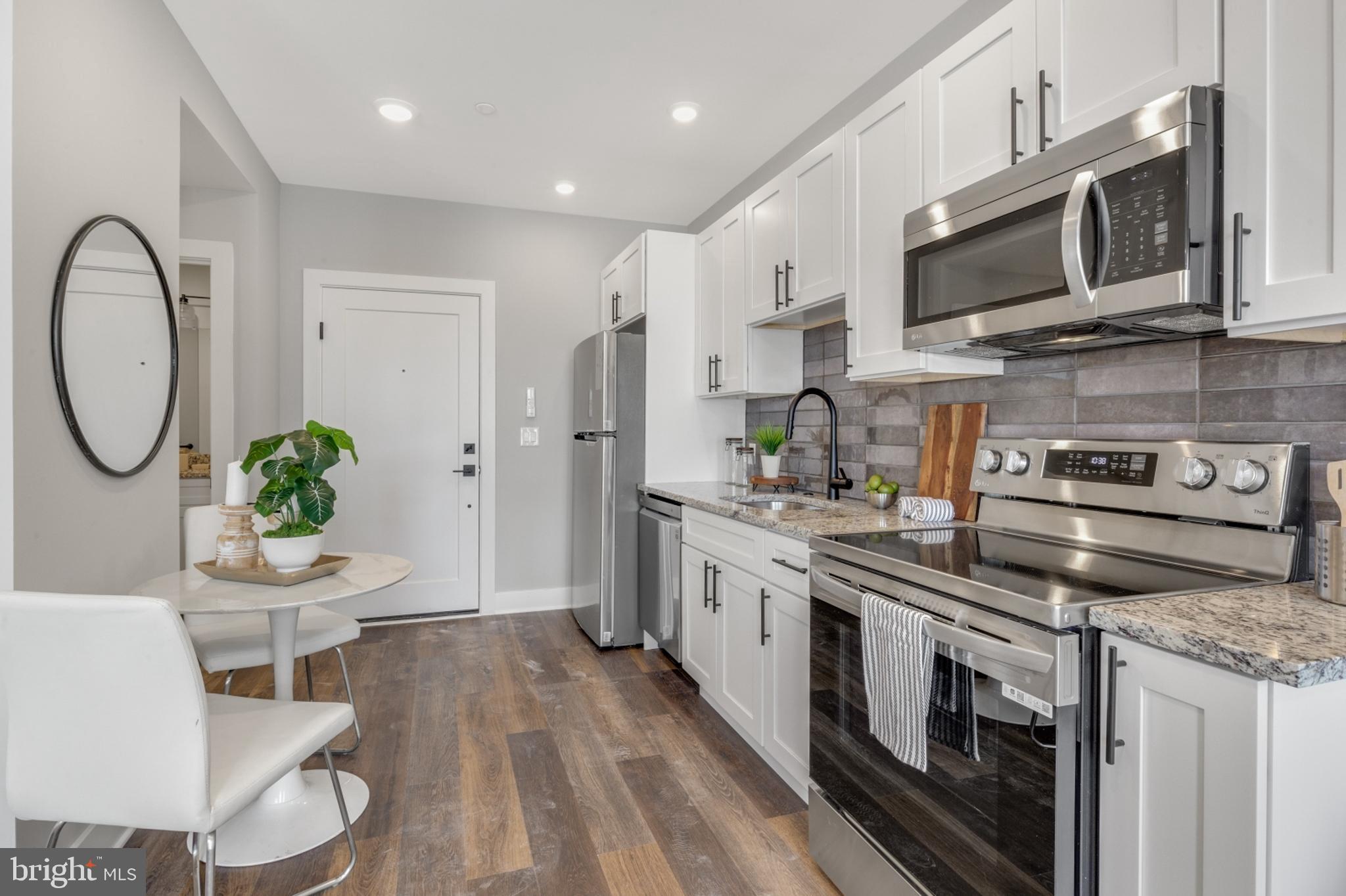 1924 North Front Street, Unit 401 Philadelphia, PA 19122 - Photo 4 of 30 a kitchen with stainless steel appliances granite countertop a stove a sink dishwasher and white cabinets with wooden floor