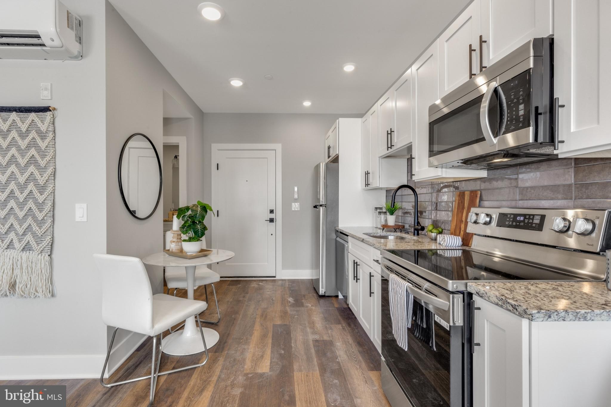 1924 North Front Street, Unit 401 Philadelphia, PA 19122 - Photo 5 of 30 a kitchen with stainless steel appliances granite countertop a stove top oven a sink dishwasher a dining table and chairs with wooden floor