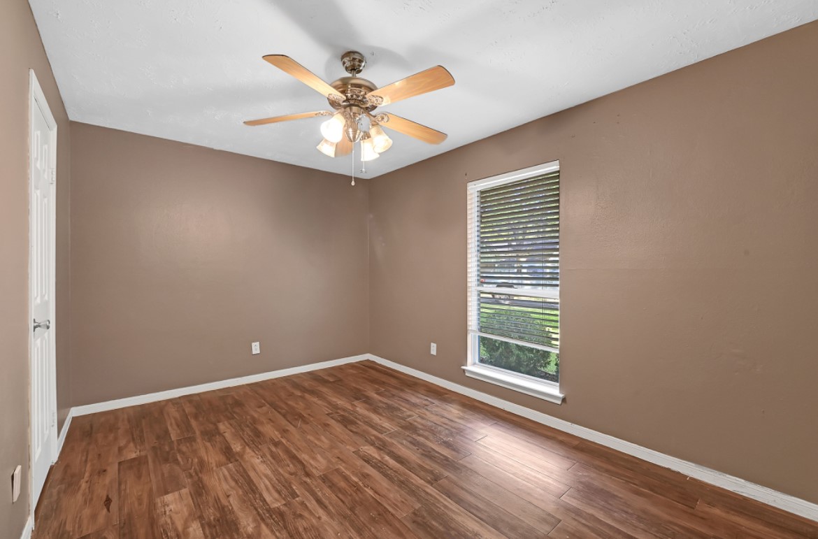 3403 Dryburgh Court Huffman, TX 77336 - Photo 5 of 18 an empty room with wooden floor fan and windows