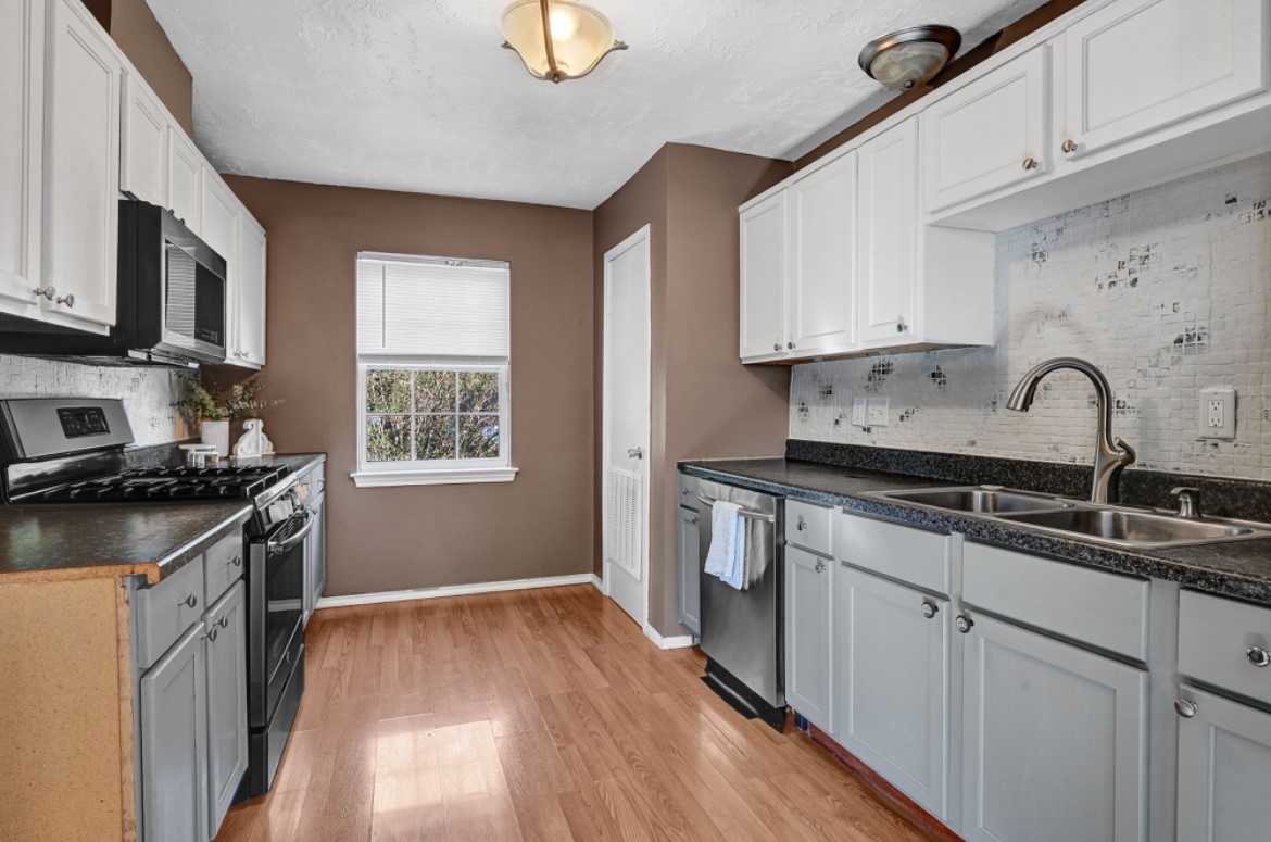 3403 Dryburgh Court Huffman, TX 77336 - Photo 10 of 18 a kitchen with stainless steel appliances granite countertop a sink stove refrigerator and white cabinets with wooden floor