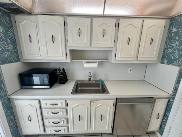 a kitchen with white cabinets a sink and dishwasher