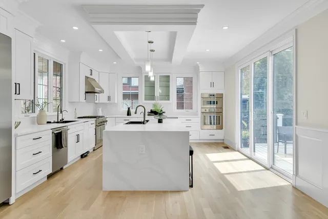 a large white kitchen with a large window and stainless steel appliances