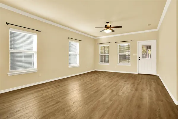 a view of empty room with wooden floor and fan
