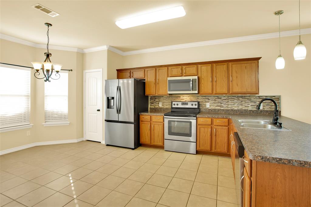 4813 Pinnacle Place Denison, TX 75021 - Photo 13 of 28 a kitchen with granite countertop a refrigerator and a stove top oven