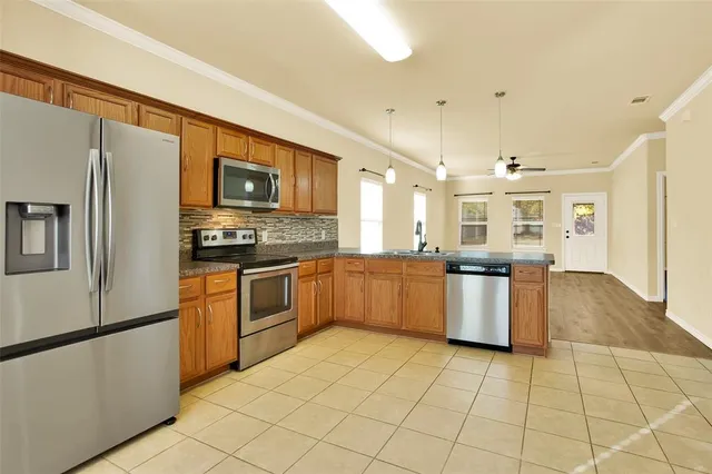 a large kitchen with stainless steel appliances granite countertop a refrigerator a stove top oven and a sink