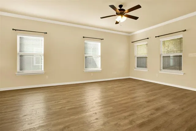 a view of an empty room with window and wooden floor
