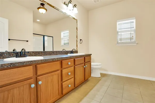 a spacious bathroom with a granite countertop sink a toilet a mirror and a window