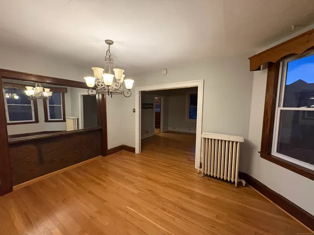 a view of a hallway with wooden floor and chandelier