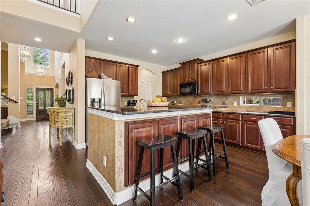 960 Remuda Road Frisco, TX 75033 - Photo 12 of 39 Expansive kitchen featuring wood-finish flooring, dark wood cabinetry, and a central island with a granite-style countertop