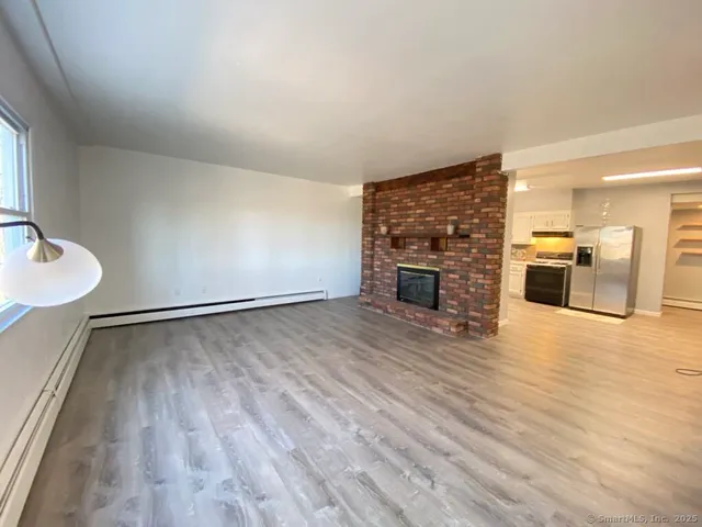 an empty room with wooden floor fire place and windows