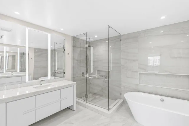 a bathroom with a tub sink shower and mirror