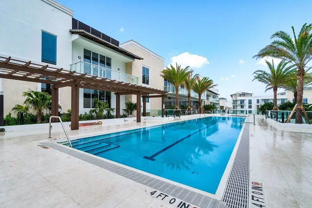 a view of a swimming pool with a yard and palm trees