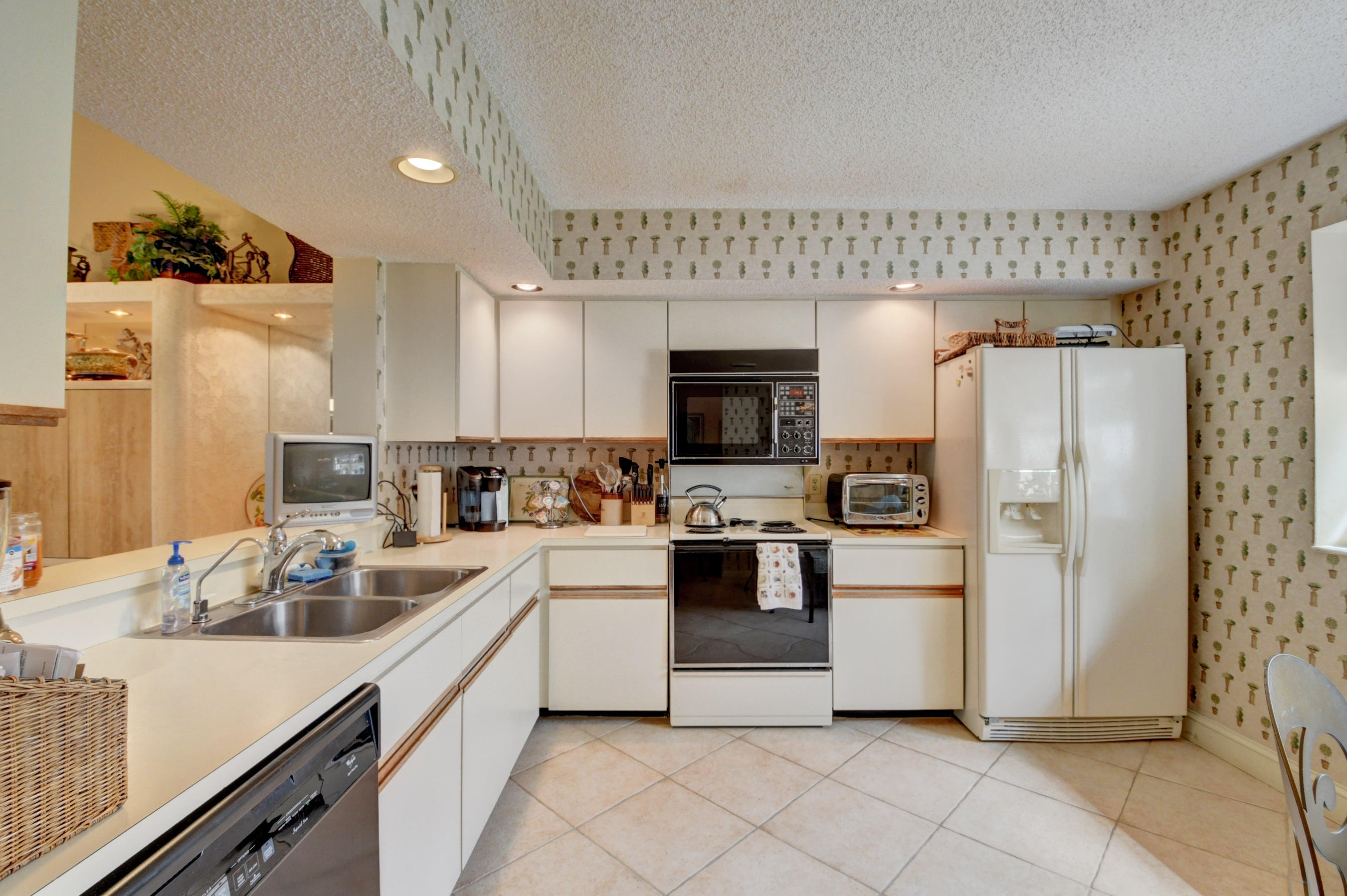 7861 La Mirada Drive Boca Raton, FL 33433 - Photo 16 of 26 a kitchen with white cabinets and white appliances