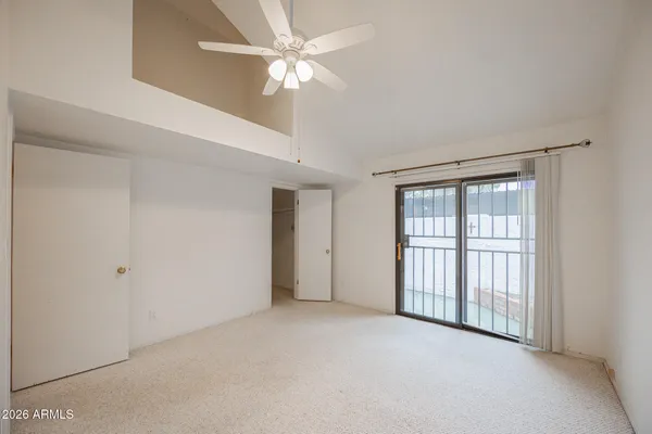 an empty room with chandelier fan and windows