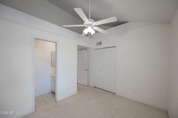an empty room with closet and a ceiling fan