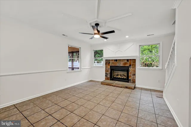 a view of an empty room with a fireplace and a chandelier fan
