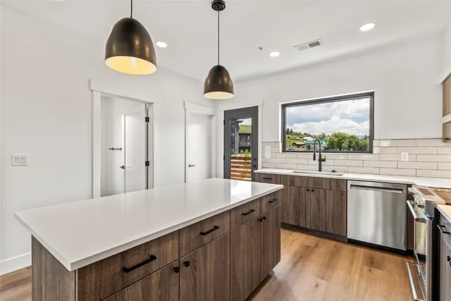 a kitchen with stainless steel appliances a sink a center island and a window