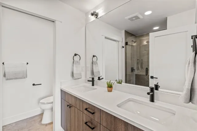 a bathroom with a double vanity sink toilet and a mirror