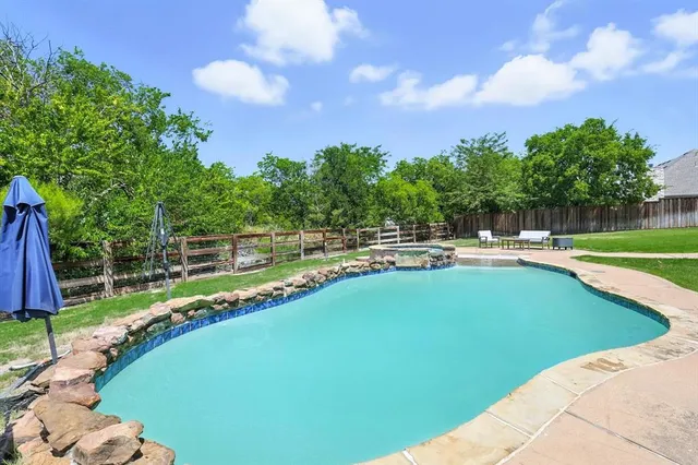 an aerial view of a house with swimming pool and large trees