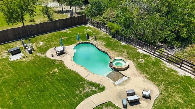 an aerial view of a swimming pool with outdoor seating and yard