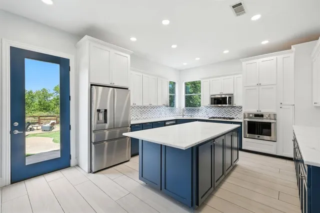 a kitchen with stainless steel appliances granite countertop a table chairs sink and cabinets