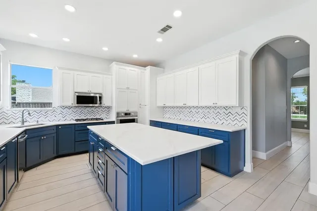 a kitchen with stainless steel appliances granite countertop a refrigerator a sink dishwasher and white cabinets with wooden floor