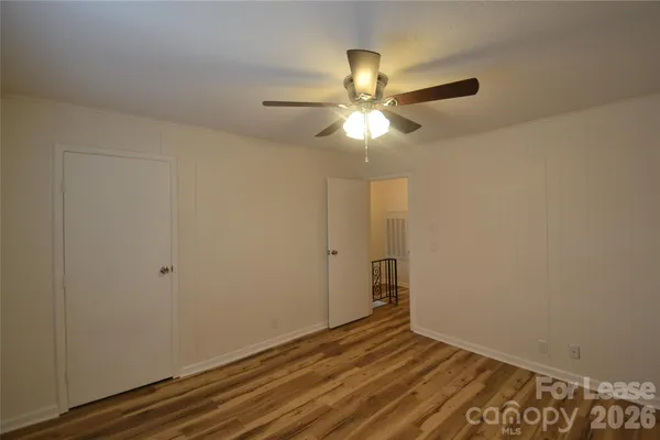 an empty room with wooden floor fan and windows