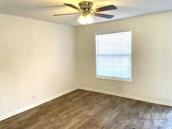an empty room with a window and a fan