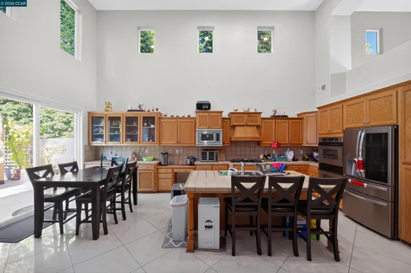 a open kitchen with stainless steel appliances granite countertop a stove top oven a dining table and chairs with the living room
