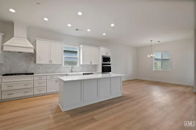 a large kitchen with stainless steel appliances granite countertop a stove a sink and white cabinets