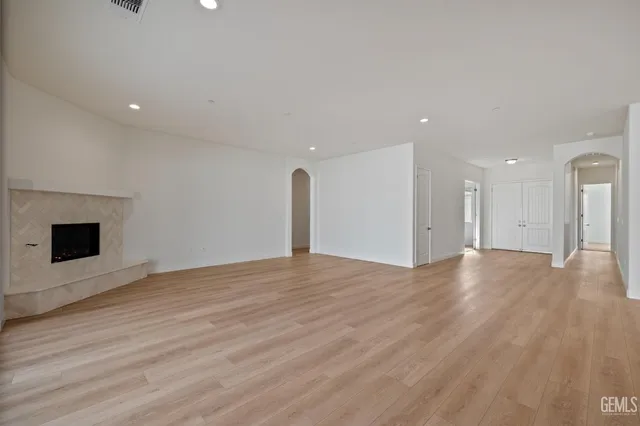a view of an empty room with wooden floor and a fireplace