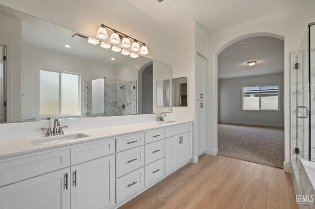 a spacious bathroom with double vanity a mirror a vanity and a shower