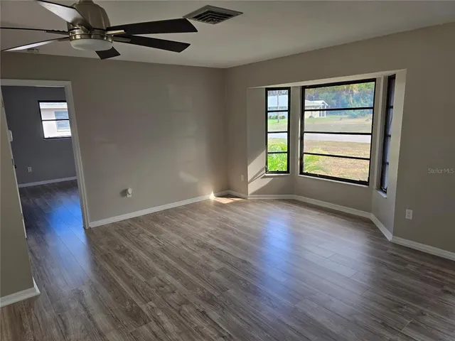 an empty room with wooden floor cabinet and windows