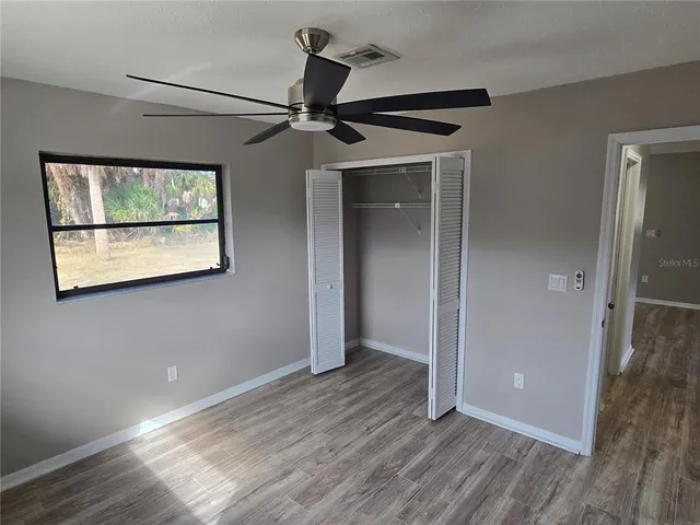 an empty room with wooden floor fan and windows