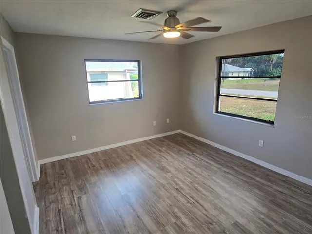 a view of an empty room with a window and wooden floor