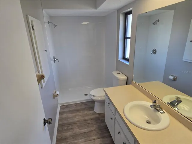 a bathroom with a granite countertop sink toilet and shower a mirror