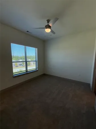an empty room with windows and fan