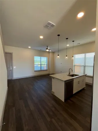 a large white kitchen with kitchen island wooden floors granite counter tops and a window