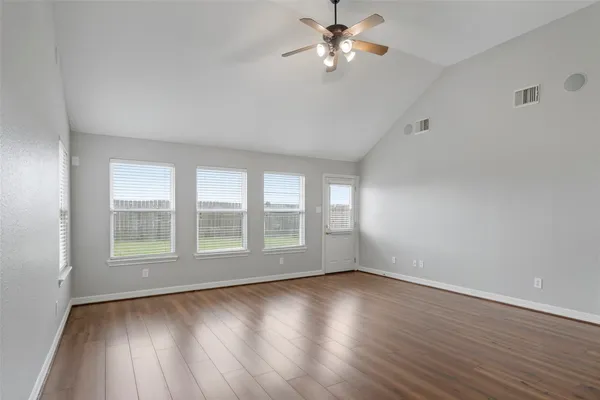 an empty room with wooden floor chandelier fan and windows