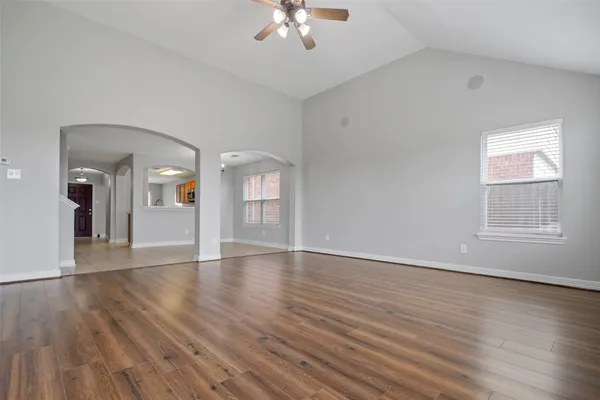 a view of an empty room with wooden floor and a window