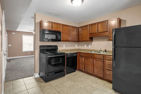 a kitchen with granite countertop a refrigerator and a stove top oven
