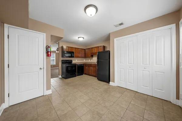 an empty room with kitchen view and a refrigerator