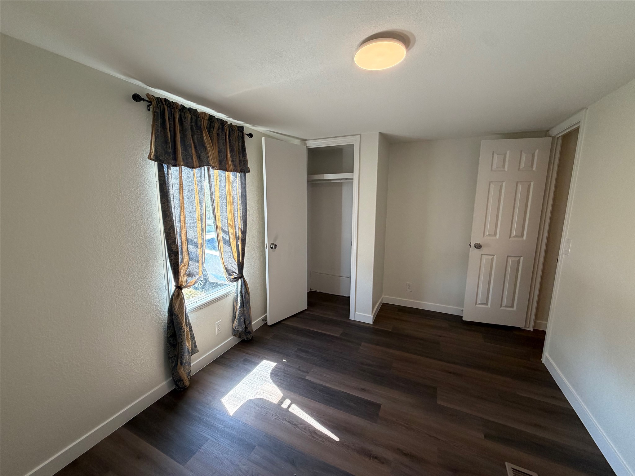 104 Castillo Street Kyle, TX 78640 - Photo 7 of 9 2nd bedroom Rich wood plank flooring and a classic six-panel door define this comfortable bedroom.
